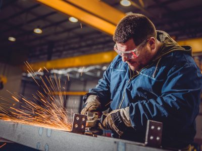 Worker Using Angle Grinder in Factory and throwing sparks