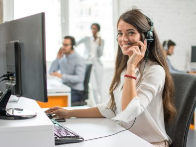 Young friendly operator woman agent with headsets working in a call centre.