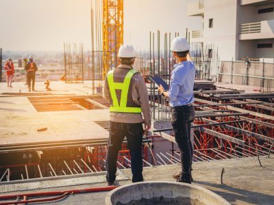 Structural engineer and foreman worker with touch pad discuss, plan working for the outdoors building construction site.
