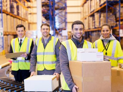 Workers smiling by conveyor belt in warehouse